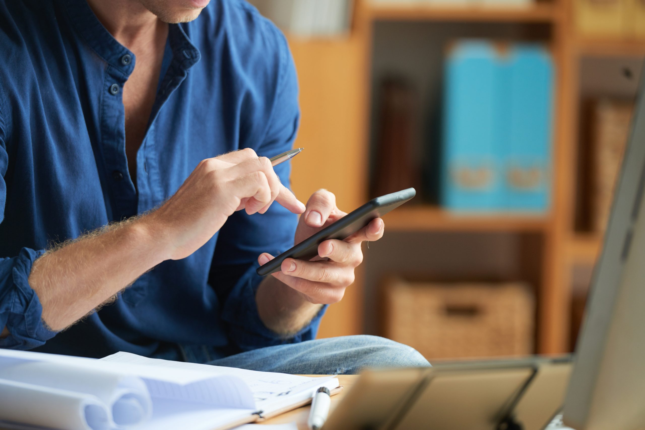 casually dressed unrecognizable man using smartphone work office