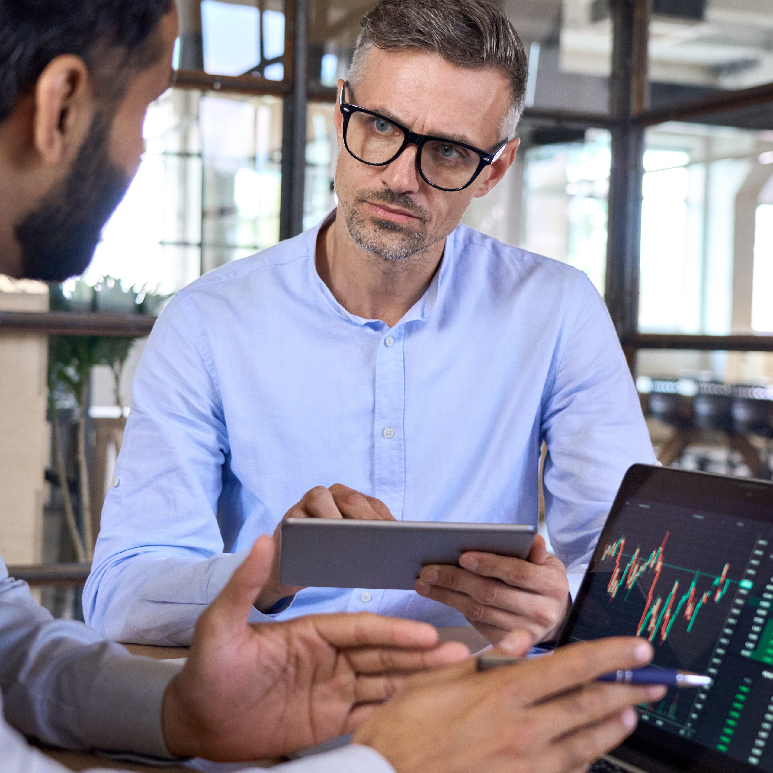 Two traders brokers stock exchange market investors discussing crypto trading chart using digital tablet and laptop analyzing financial risks and cryptocurrency growth forecasts for investment profit.